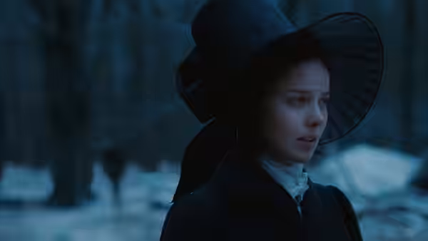 Fanny Brawne (Abbie Cornish) walks through snowy woods in a wide-brimmed black hat