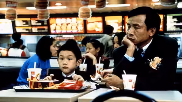 NJ sits with Yang-Yang in a fast-food restaurant, resting his cheek on one hand