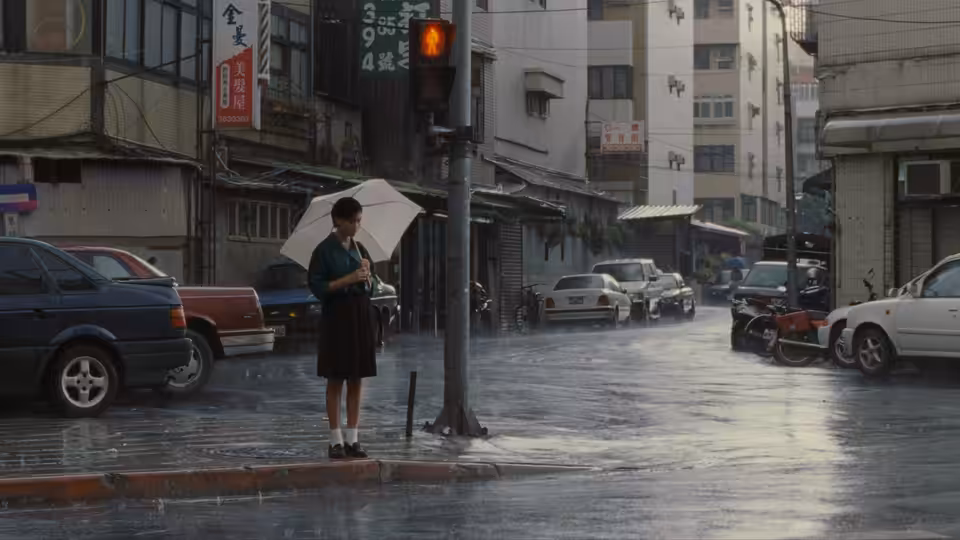 Ting-Ting stands beneath an umbrella at a rain-soaked city intersection
