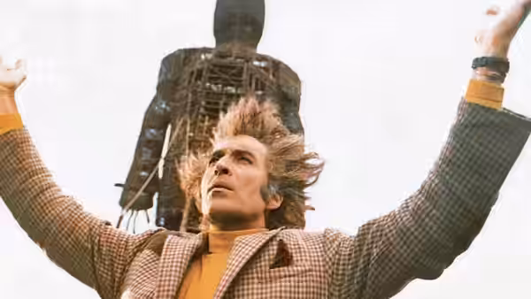 Sergeant Neil Howie (Edward Woodward) raises his arms before the wicker man