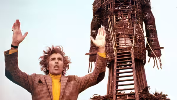 Sergeant Neil Howie (Edward Woodward) raises his arms before the wicker man