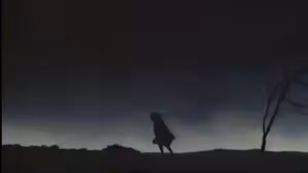 A lone figure walking across a barren hill under a dark twilight sky