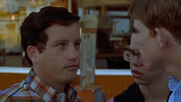 two young men face each other in close conversation inside a diner