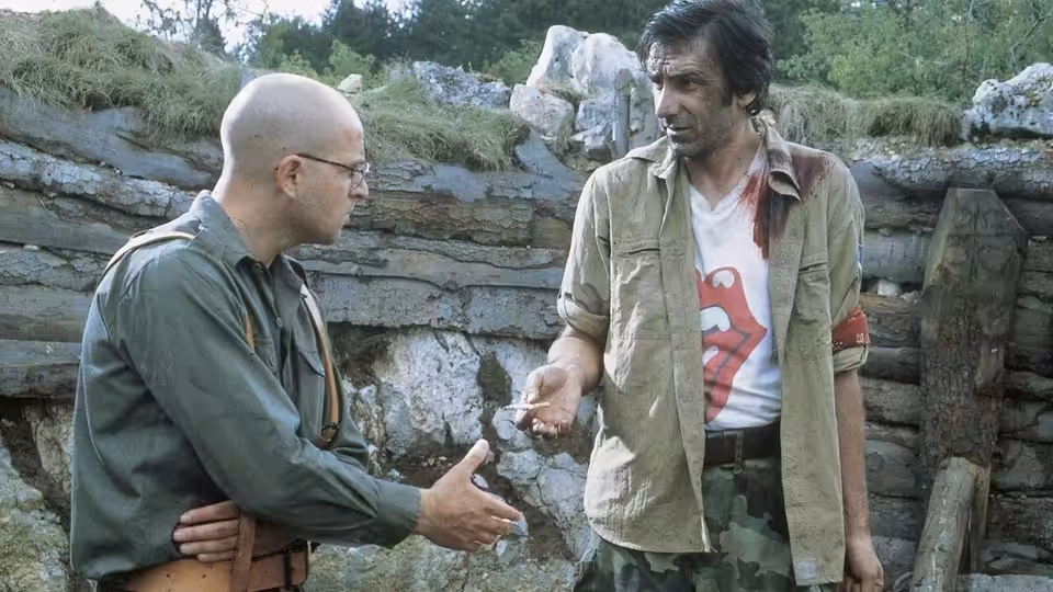 Nino (Rene Bitorajac) reaches toward bloodied Ciki (Branko Đurić) inside a ruined trench