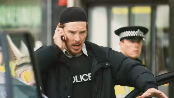 Negotiator (Benedict Cumberbatch) speaking on phone beside a police car