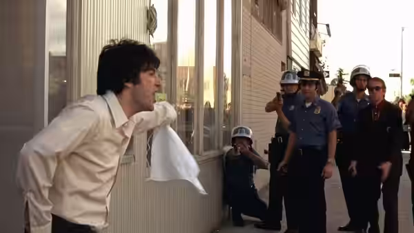 Sonny (Al Pacino) leans against a building as police officers stand nearby