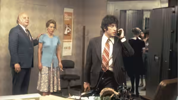 Sonny (Al Pacino) speaks on the telephone inside a bank while two others watch