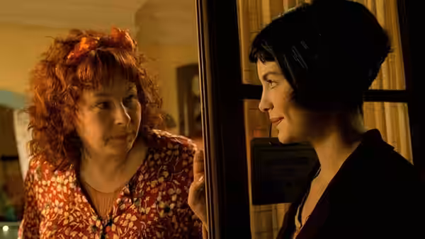 Amélie (Audrey Tautou) stands at a doorway facing a red-haired woman
