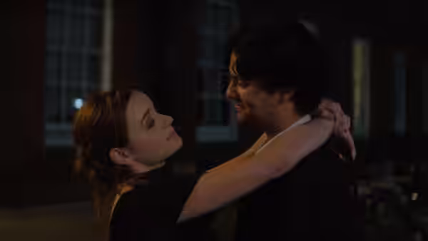 A young woman embracing a man at night outside a building