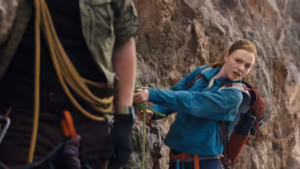 Shiloh Hunter (Virginia Gardner) adjusts climbing gear on a steep rock wall