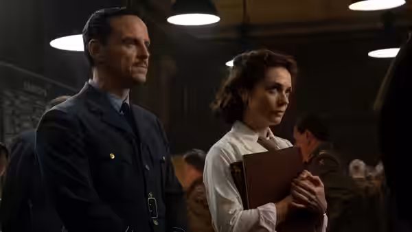 James Stagg (Andrew Scott) stands beside woman holding brown folder