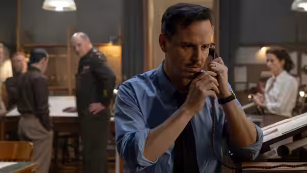 James Stagg (Andrew Scott) speaks into telephone in busy office
