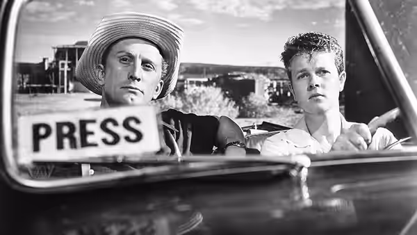 Charles Tatum (Kirk Douglas) and Herbie Cook (Robert Arthur) seated in a car with a press sign