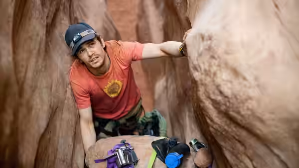 Aron Ralston (James Franco) climbing through a narrow red rock canyon
