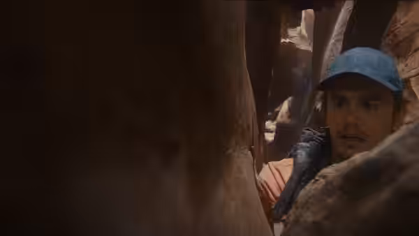 Aron Ralston (James Franco) peering from a narrow slot canyon