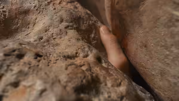 a hand wedged between two large rock surfaces in a canyon