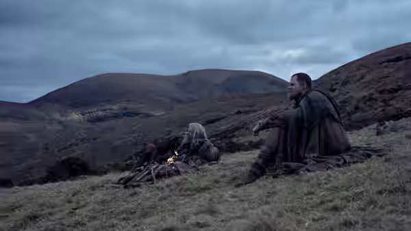 Robin Hood and Little John resting by a campfire in hills