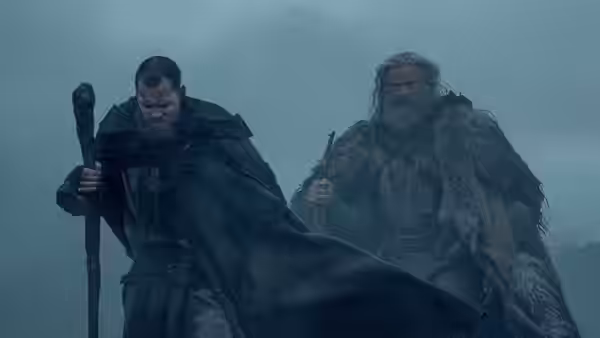 Little John (Bill Skarsgård) and Robin Hood walking through mist