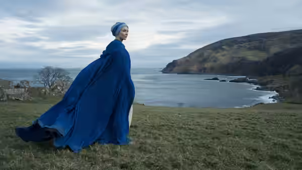 Sister Brigid (Jodie Comer) in a blue cloak overlooking the sea