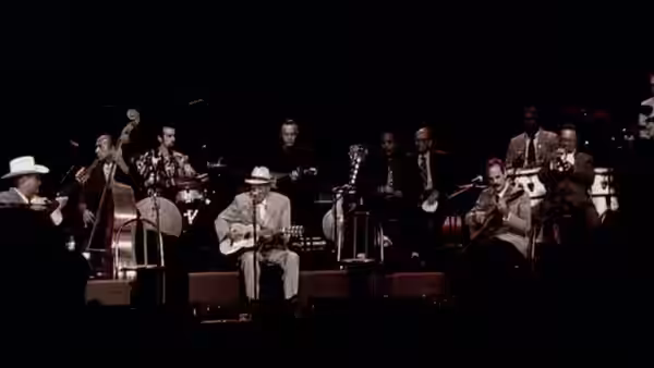 Large band performing on stage with guitars brass and Ry Cooder in white hat