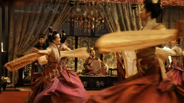 Dancers in traditional attire performing before seated musicians in a hall