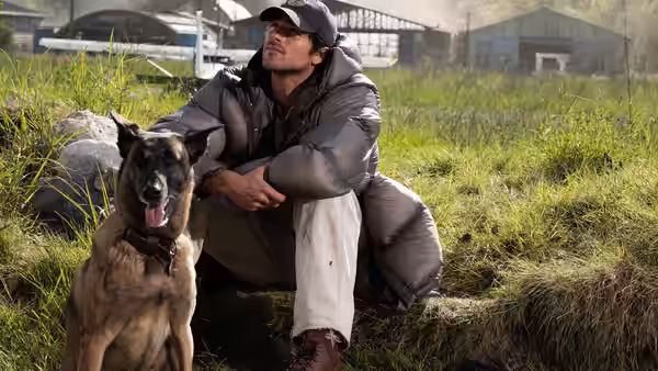 Hig (Jacob Elordi) sitting in a field with a dog beside him