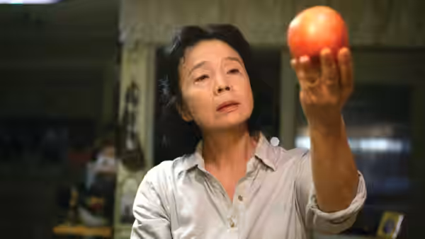 Yang Mi-ja (Yoon Jeong-hee) holding a red apple up to examine it