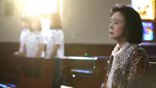 Yang Mi-ja (Yoon Jeong-hee) sitting in a pew inside a church