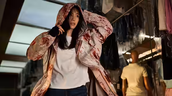 Kwon Se-jeong (Gianna Jun) adjusting her bloodied hood inside a store