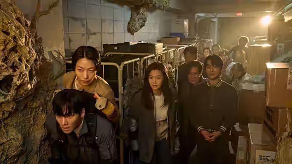 group of survivors standing alert in a ruined underground facility