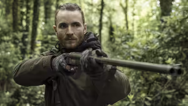 The Survivalist (Martin McCann) aims a shotgun through the forest