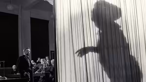 Frederick Treves (Anthony Hopkins) stands beside a large shadow on a curtain