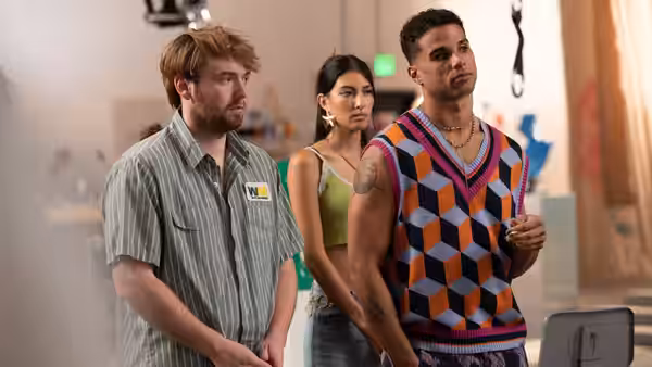 Three young adults stand side by side in a brightly lit room