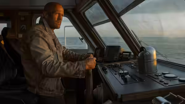 Cole Reed (Jason Statham) steering a ship at the helm