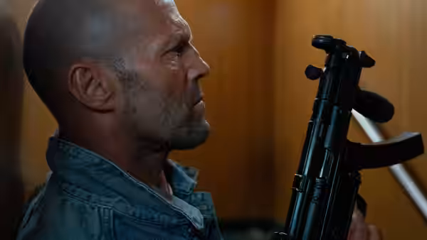 Cole Reed (Jason Statham) holding a submachine gun indoors