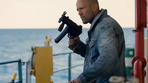 Cole Reed (Jason Statham) aiming a gun on a ship's deck