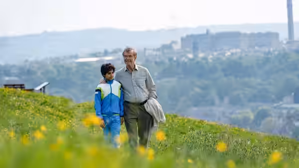 Brendan Ingle (Pierce Brosnan) walks with a young boy across a grassy hill