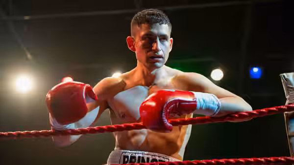 Naz (Amir El-Masry) leans on the ropes inside a boxing ring
