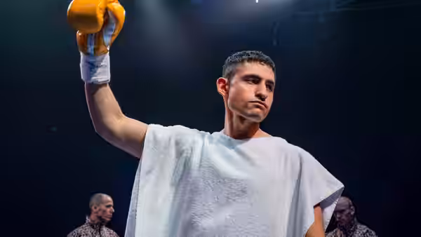 Naz (Amir El-Masry) raises a yellow glove after a fight