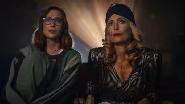 Kris and Billy seated side by side in a dark theater