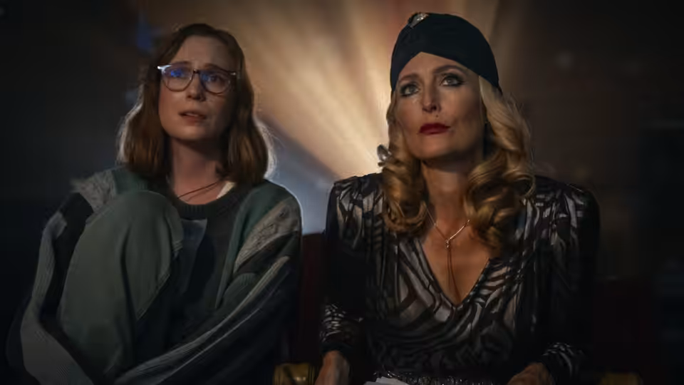 Kris and Billy seated side by side in a dark theater