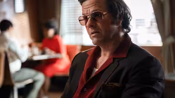 Gregory Scarpa (Mark Wahlberg) sits in a diner booth wearing sunglasses