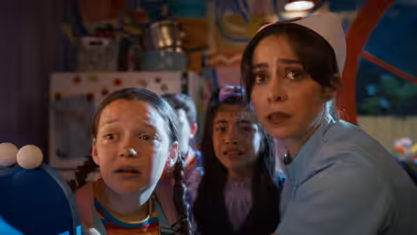 Grace (Cristin Milioti) and two girls staring in alarm inside a colorful room