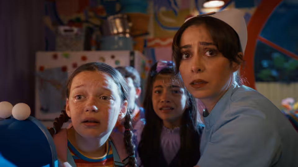 Grace (Cristin Milioti) and two girls staring in alarm inside a colorful room