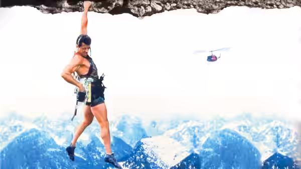 Gabe Walker (Sylvester Stallone) dangling from a cliff near a helicopter