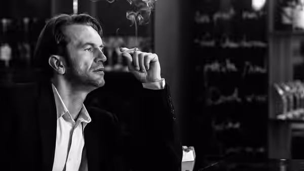 Wiktor (Tomasz Kot) smokes a cigarette in a dimly lit bar
