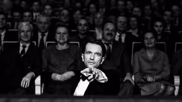 Wiktor (Tomasz Kot) gestures from his seat in a theater audience
