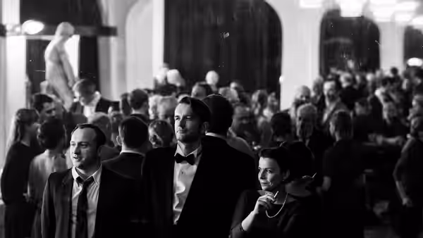 Wiktor (Tomasz Kot) stands among guests at a formal reception