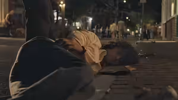 Tony (Dominic Sessa) lying on a city street at night