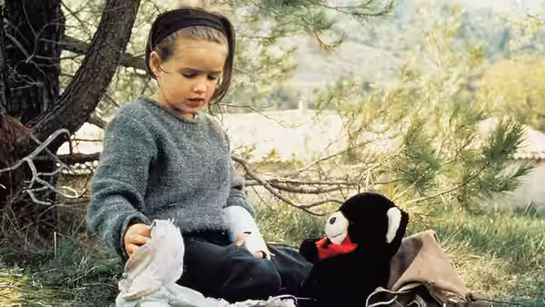 Ponette (Victoire Thivisol) sits beneath a tree beside her stuffed rabbit